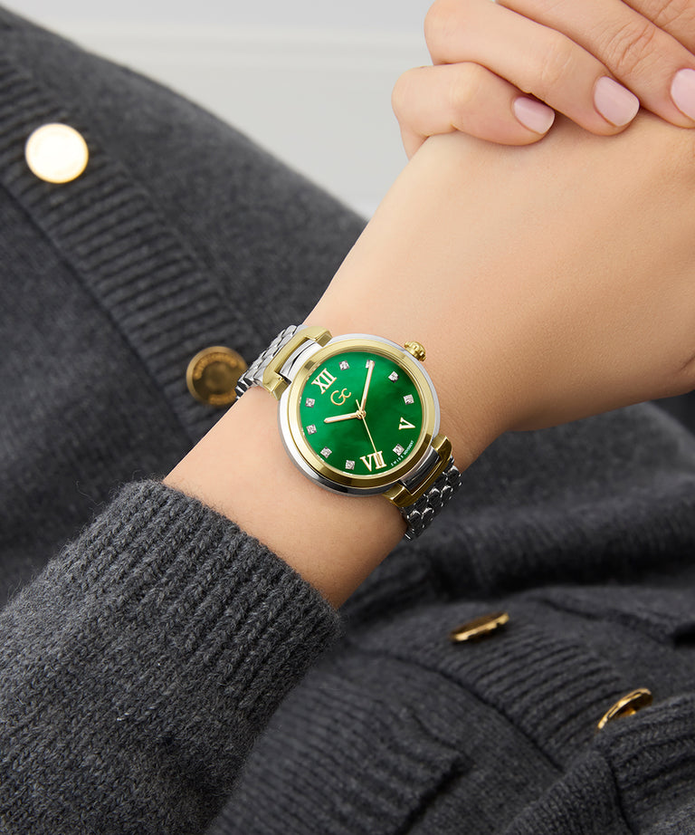 Gc Allure Mid Size Metal Green watch on a person's wrist with a gray coat background