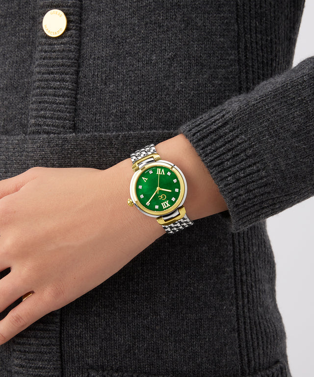 Hand wearing a Gc Allure Mid Size Metal watch with a green face and gold accents on a dark gray background