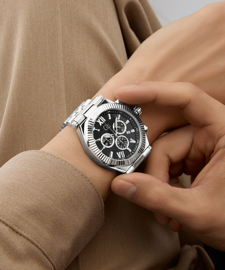 Person wearing a Gc Atlas Chrono Metal watch with a black face on a beige background