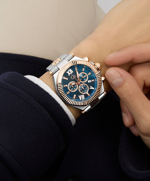 Close-up of a wrist wearing a silver and rose gold Gc Atlas Chrono Metal watch with a blue face.