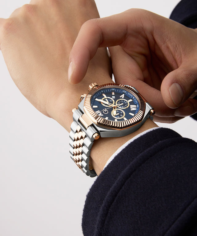 Close-up of a hand wearing a Gc Atlas Chrono Metal watch with a blue face and rose gold accents.