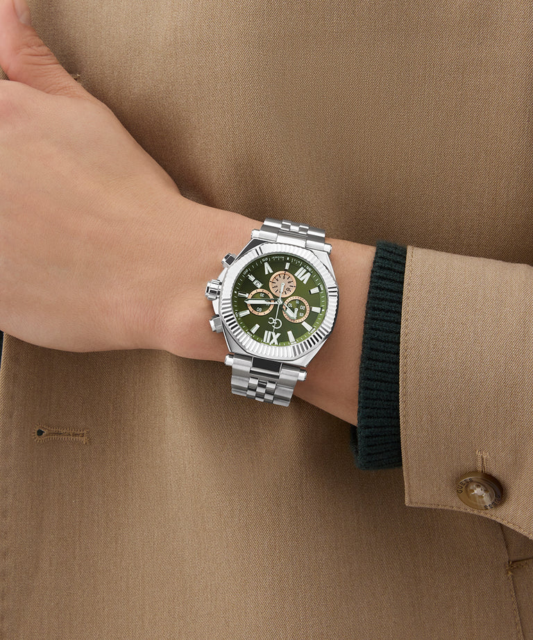 Hand wearing a Gc Atlas Chrono Metal silver watch with a green face on a brown background