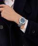 Person wearing a Gc Legacy Sleek Metal watch with a dark blue face and silver bracelet on a dark background