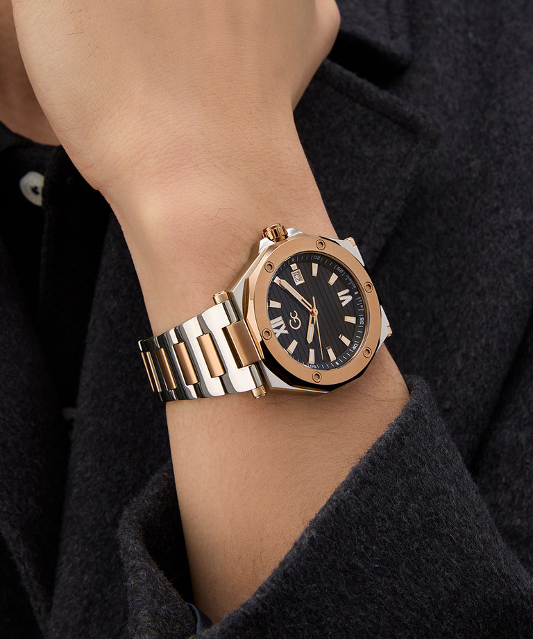 Rose gold and silver Gc Legacy Sleek Metal watch on a wrist with a dark background