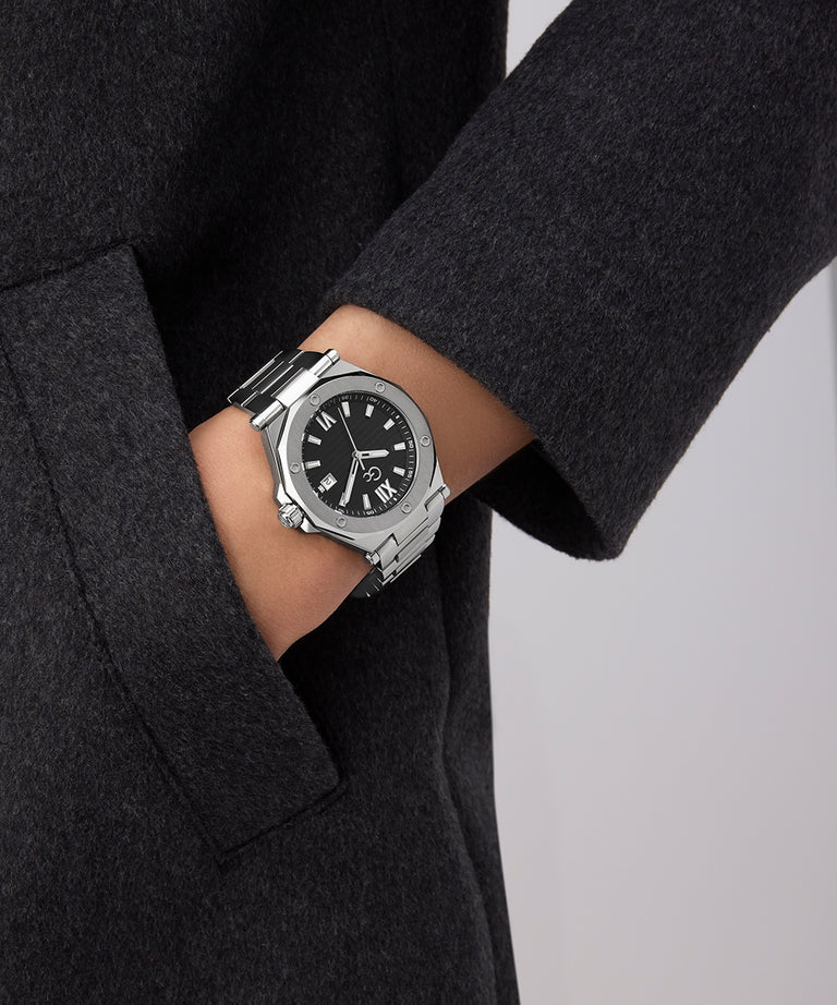 Person wearing a Gc Legacy Sleek Metal watch with a black face on a gray background