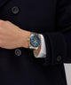 Person wearing a dark coat with a Gc IdolSport Chrono Metal watch on their wrist, set against a neutral background
