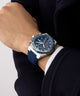 Close-up of a person wearing a blue and silver Gc IdolSport Chrono Silicone watch on a plain background