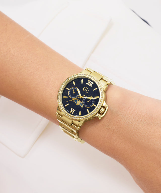 Gold Gc MoonChic Large Size Metal with a black face on a wrist against a white background