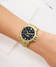 Gold Gc MoonChic Large Size Metal with a black face on a wrist against a white background