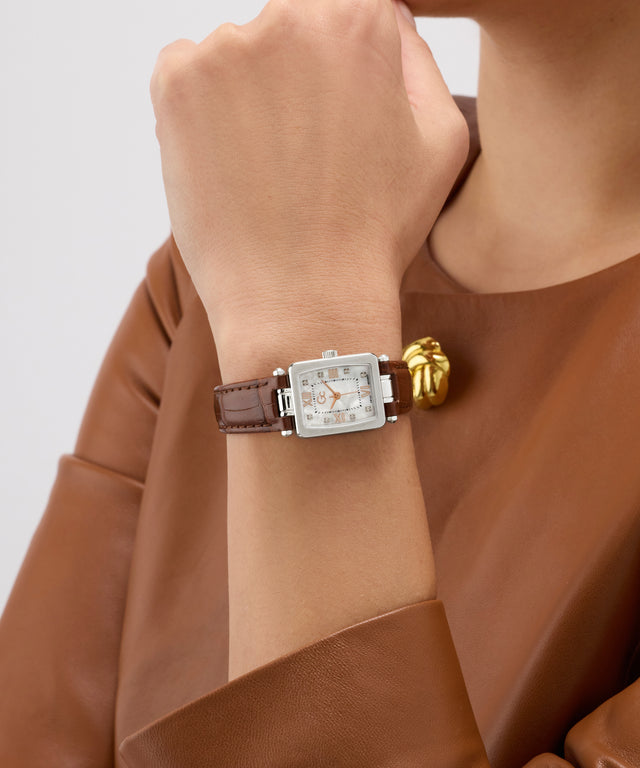Gc Plaza Mini Small Size Leather Watch with a brown strap and gold accents on a wrist, wearing a brown coat against a light background