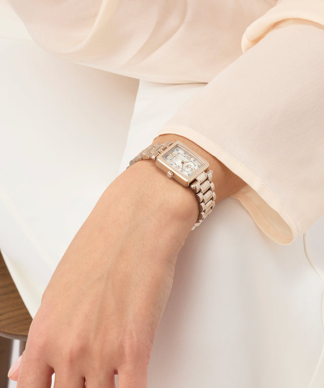 Close-up of a hand wearing a diamond-encrusted Gc Plaza Mini Small Size Metal watch on a plain background