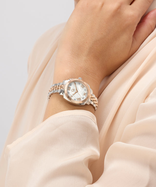 Close-up of a wrist wearing a rose gold Gc Flair Coussin Mini Small Size Metal with a light background
