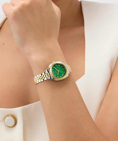 Gold and silver Gc Flair Coussin Mini Small Size Metal with green face on a wrist against a white background