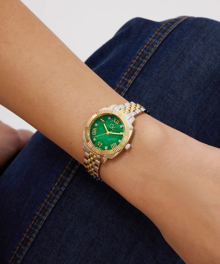 Gold and green Gc Flair Coussin Mini Small Size Metal on a wrist with a denim background