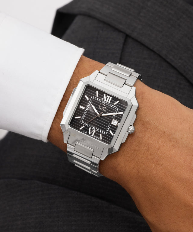 Silver Gc SquareCut Metal watch with a black face on a person's wrist, wearing a suit.
