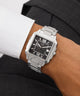 Silver Gc SquareCut Metal watch with a black face on a person's wrist, wearing a suit.