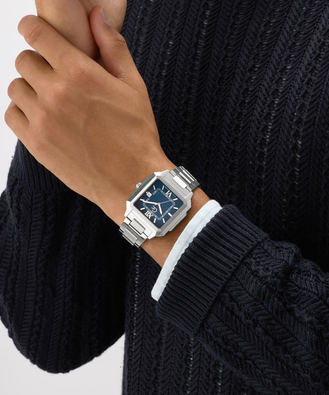 Hand wearing a Gc SquareCut Metal watch with a dark face on a white background