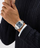 Hand wearing a Gc SquareCut Metal watch with a dark face on a white background