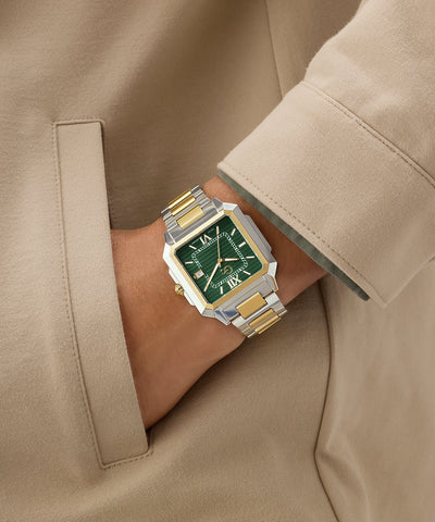 Gold and silver Gc SquareCut Metal watch with green face on a wrist, wearing a beige coat.