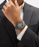 Person wearing a Gc TechnoForce Chrono Metal watch on a gray suit background