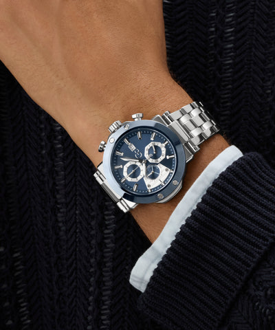 Silver Gc TechnoForce Chrono Metal watch with a blue face on a wrist, wearing a black sweater.