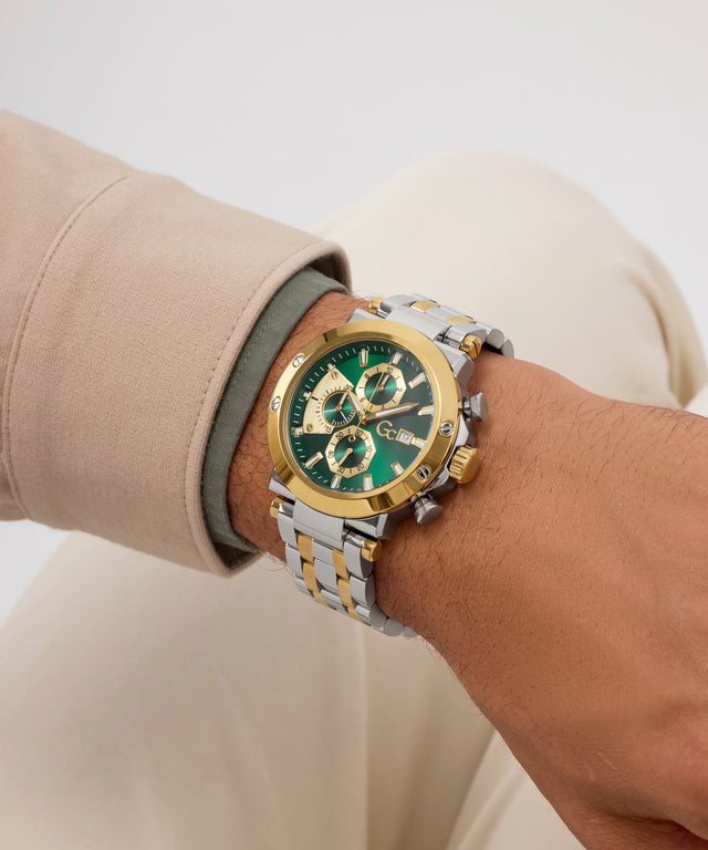 Gold and silver Gc TechnoForce Chrono Metal watch with green face on a wrist against a neutral background