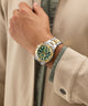 Hand wearing a gold and silver Gc IronForce Chrono Metal with a green face on a beige jacket.