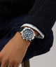 Close-up of a wrist wearing a silver Gc IronForce Chrono Silicone with a blue face, against a neutral background.