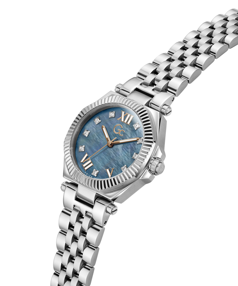 A women's stainless steel watch with a blue mother-of-pearl dial, Roman numeral hour markers, crystal diamond accents, and a matching steel link bracelet, shown on a plain white background. lifestyle