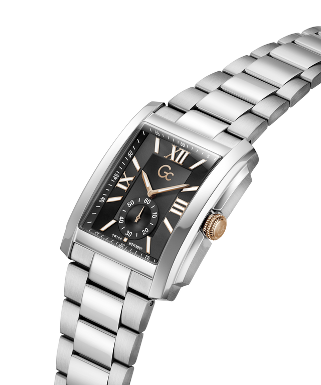 A silver stainless steel men's watch with a black dial, featuring Roman numeral hour markers, a gold-tone crown, and a matching steel link bracelet on a white background. lifestyle