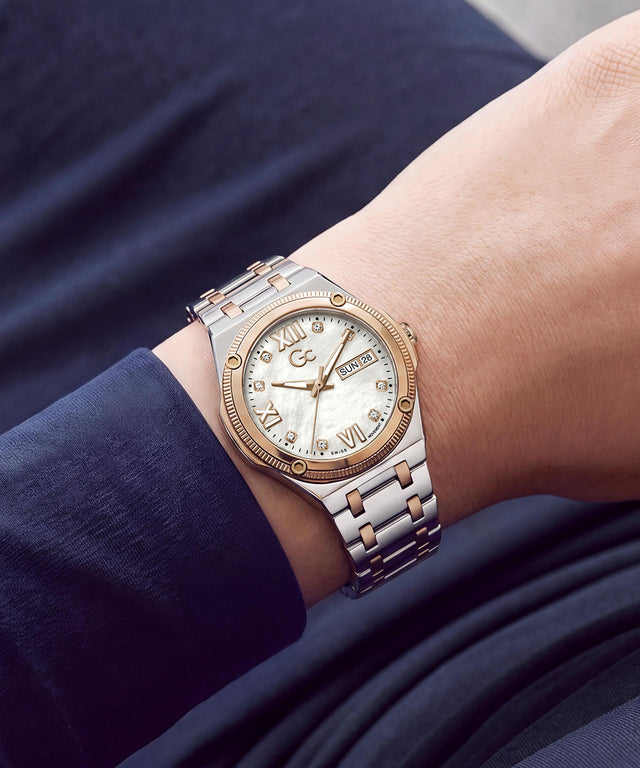 A two-tone stainless steel and rose gold wristwatch with a white dial and Roman numerals, shown worn on a person's wrist.
