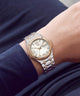 A two-tone stainless steel and rose gold wristwatch with a white dial and Roman numerals, shown worn on a person's wrist.