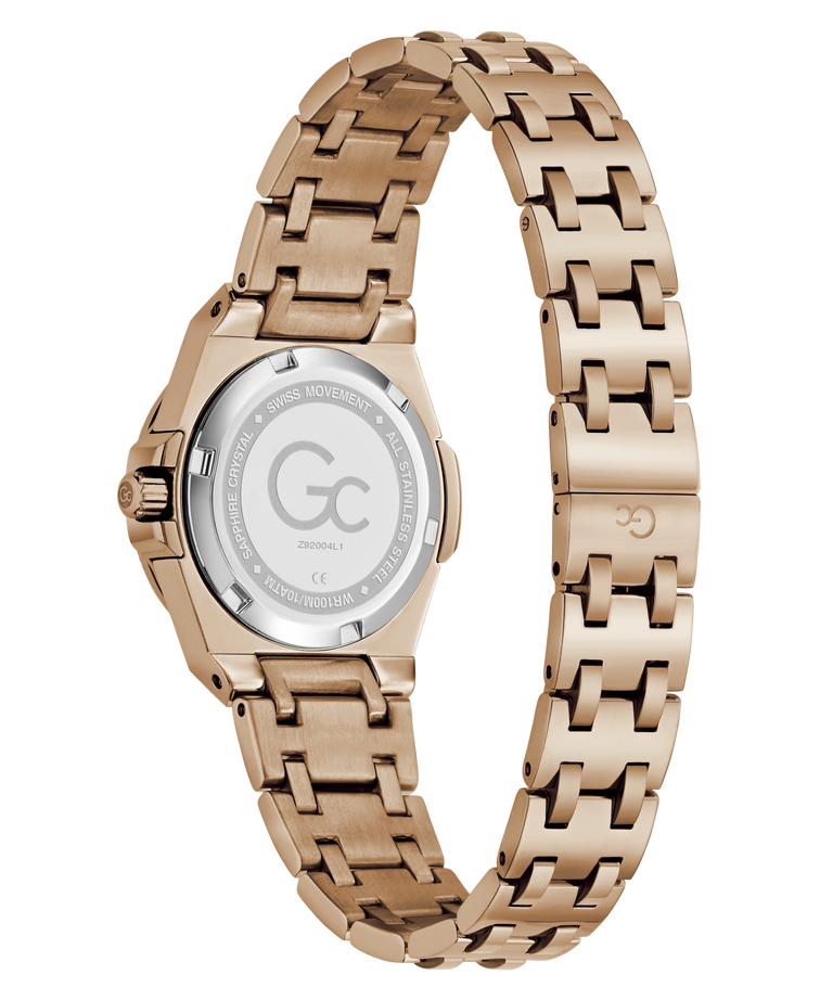 Rose gold women's watch with a stainless steel link bracelet, shown from the back on a white background. The back casing is transparent, revealing the brushed steel case and a silver-toned crystal backplate with a 'Gc' logo and technical specifications.
