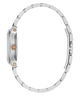 Close-up side view of a silver-tone metal watch with a matching link bracelet, featuring a textured crown guard and a small round rose gold accent on the side.