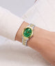A two-tone wristwatch with a green dial and green bracelet links, worn on a person's wrist. The watch has a gold-tone case and gold-tone hands, paired with a silver-tone and gold-tone two-tone link bracelet.