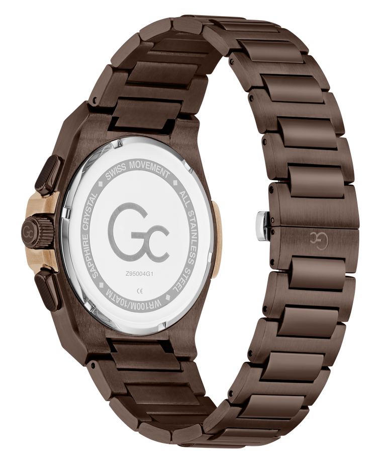 A close-up of a men's watch showing the back of the case and metal link bracelet. The watch has a dark brown anodized metal bracelet and case, with a rose gold-tone crown adjustment on the side.