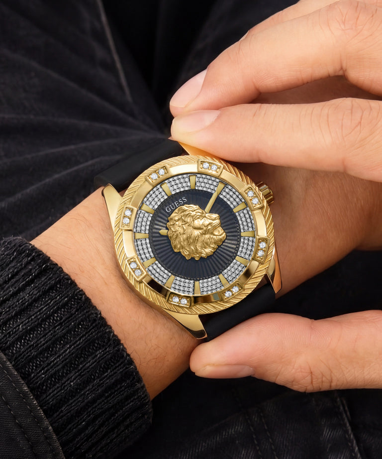 A close-up of a wrist wearing a luxury watch with a gold-tone case, a black strap, a black sunburst dial, a gold lion emblem, and crystal accents.
