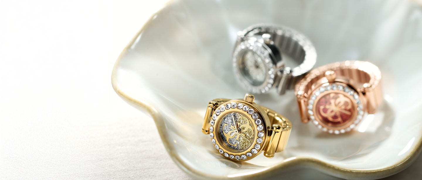 Three gold watch rings with intricate designs on a white dish.