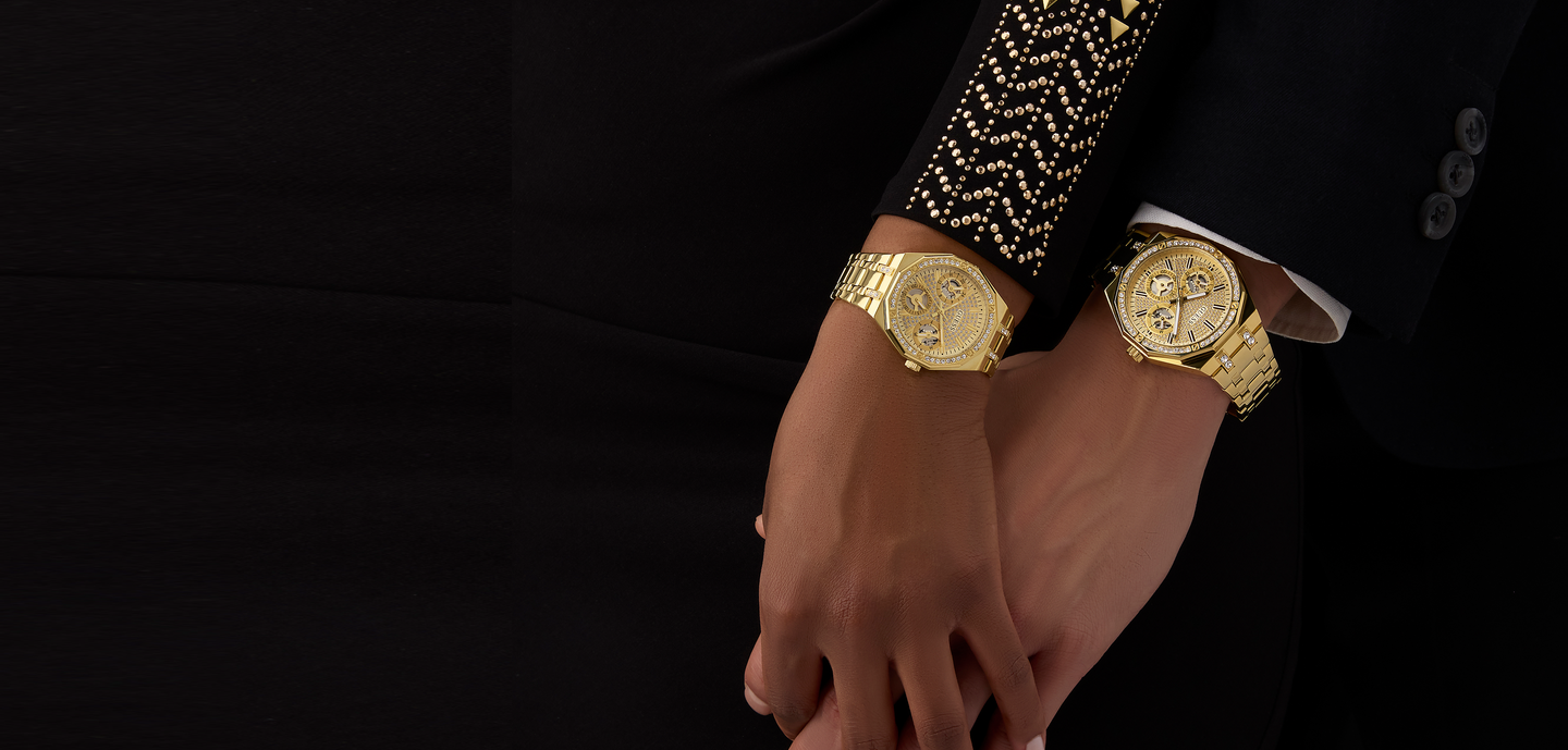 Gold wristwatch and bracelet on a couple's wrist against a black background